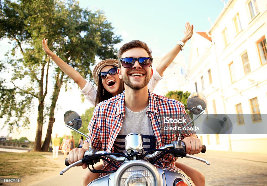 Portrait of happy young couple on scooter enjoying road trip Couple in love riding a motorbike , Handsome guy and young sexy woman travel . Young riders  enjoying themselves on trip. Adventure and vacations concept. Couple - Relationship Stock Photo