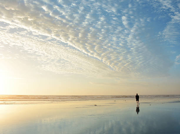 istock Man walking on the beach at sunrise. 518710978