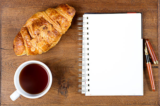 istock croissant cup coffee white book pen  on teak wood 518713762