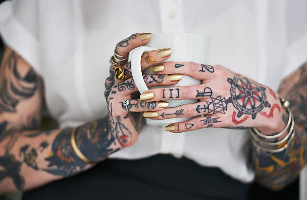 She loves her tattoos Shot of an unrecognizable tattooed businesswoman holding a mug tattoo photos stock pictures, royalty-free photos & images