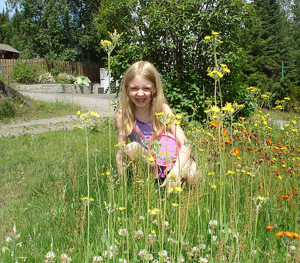 Close up of cute little girl playing in the garden in a green grass backyard.