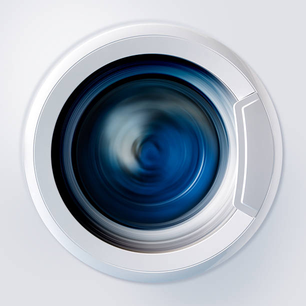 Front view and portion of the porthole of the washing machine during washing and rotation of the drum containing clothes blue