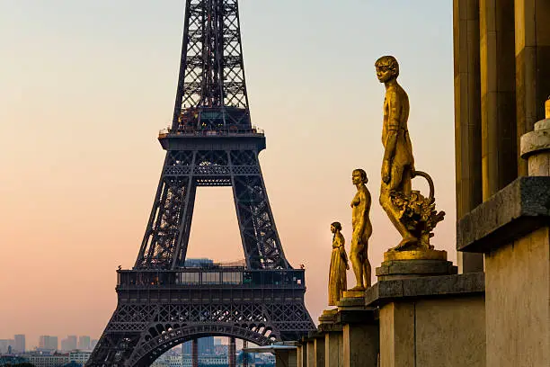 Statues at Trocadero with the Eiffel Tower in the background at sunrise.