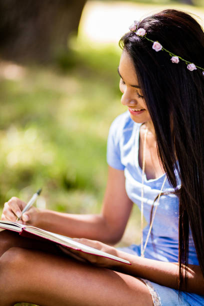istock Mixed Race Person sitting at tree writing in journal 518726594
