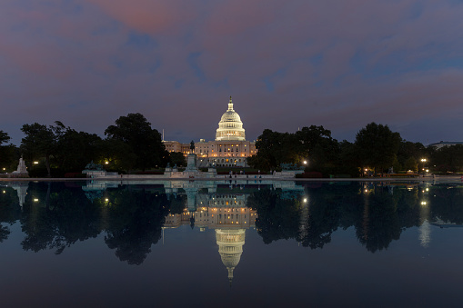 Washington DC, US Capitol Building in a cloudy sunrise with mirror reflection