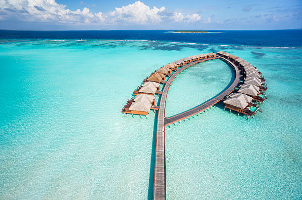 bird's eye view luxury overwater villas aerial view of luxury overwater villas in tropical lagoon of indian ocean jetty aerial stock pictures, royalty-free photos & images