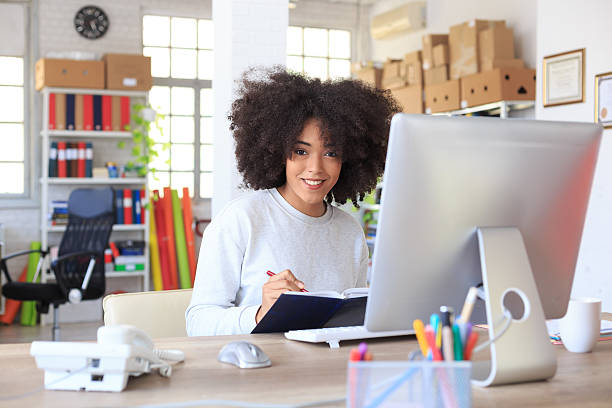 istock Happy young woman writing notes in her book 518728198