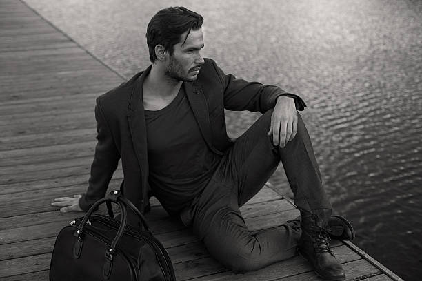 A male model posing against a wall in 50's wear.