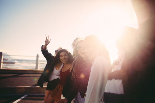 Group of friends is smiling taking a self portrait on the promenade with sun flare