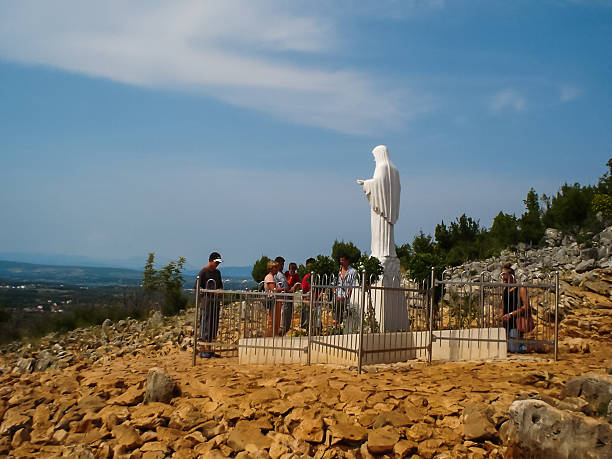 Medjugorje, Bosnia and Herzegovina - 26 July 2005 - People praying in front of the statue of Blessed Virgin Mary at the top of the hill of apparition in Medjugorje
