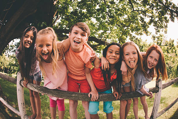 rangée d'enfants sur une barrière dans un parc de rire - summer recreation photos et images de collection
