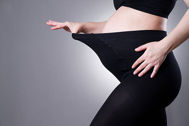 Pregnant woman in black tights for pregnant women Pregnant woman in black tights for pregnant women on gray background. Front view leggings stock pictures, royalty-free photos & images