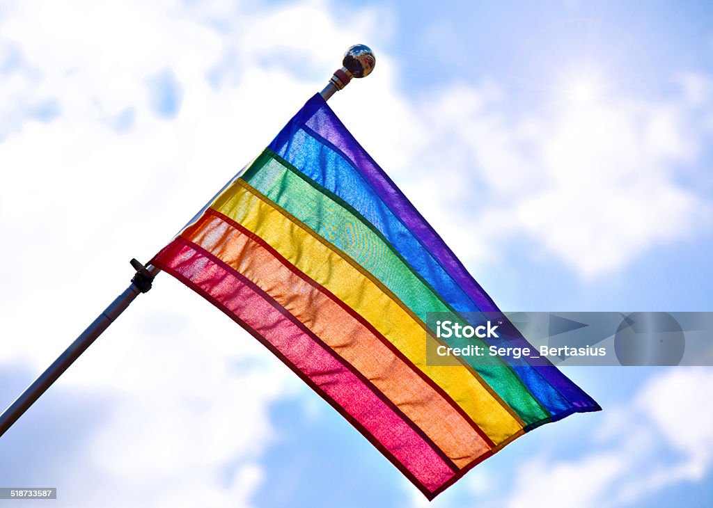 Gay Pride Flag Rainbow Gay Pride Flag waiving on sunny cloudy blue sky background Blue Stock Photo