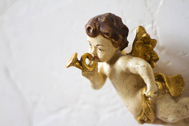 Sweet Antique Cherub With Gold Trumpet A 19th-century cherub-angel playing a gold trumpet, made by an unknown sculptor in Sicily. Plenty of copy space on the white wall. winged cherub stock pictures, royalty-free photos & images