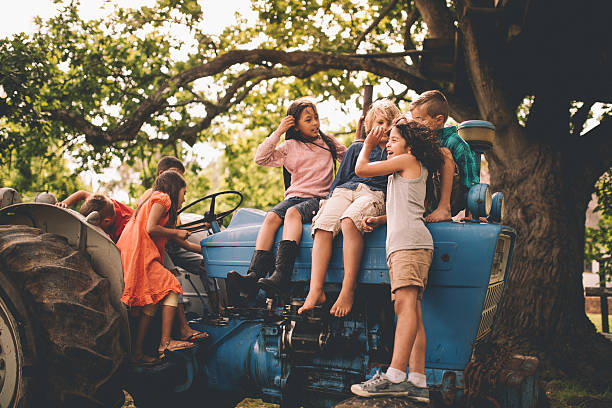 las niñas y niños jugando en una antigua tractor en árbol - school farm fotografías e imágenes de stock