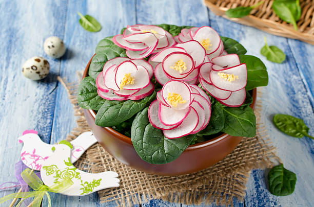 Vegetable salad Violet on blue wooden table. Salad decorated with flowers from radish and spinach leaves