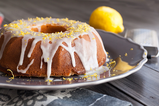 Delicious fresh rustic lemon cake covered with icing with lemon zest on top.