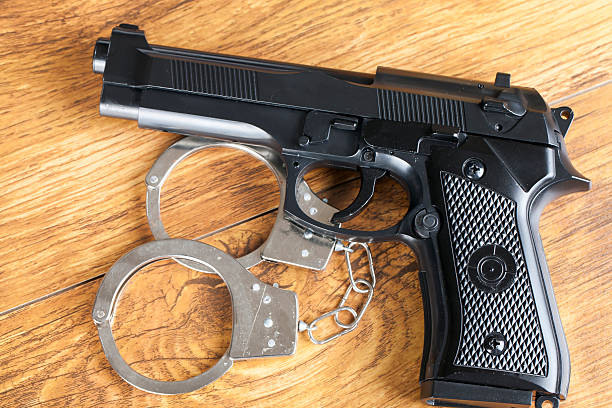 istock Handgun and handcuffs on wooden background 518754965