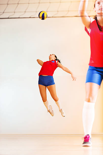Teenage volleyball player serving in the beginning of the match.   