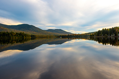 A view looking across a small lake to forested mountains. This is located in the Maine North Woods Highlands Region, Maine, USA.