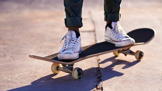 A cropped shot of a woman standing on a skateboard