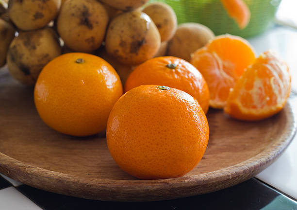 istock fresh orange tangerines and thai fruit on wood plate 518758175