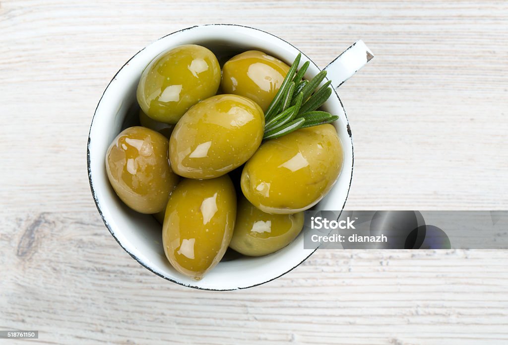 green olives in a metallic cup on wooden surface Marinated Stock Photo