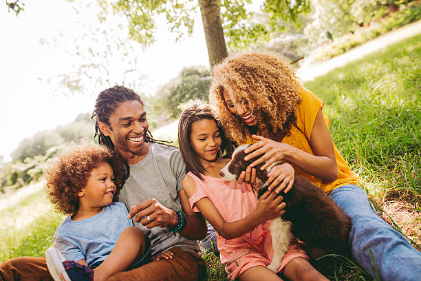 Multi-ethnic family spending time at park with new adorable pet Family spends a day in the park with their cute new border collie puppy for the first time. black man blonde hair stock pictures, royalty-free photos & images