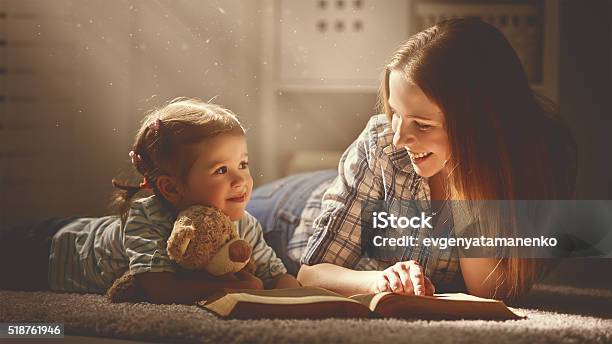 Familia Feliz Madre Con Hija Lea Un Libro En La Noche Foto de stock y más banco de imágenes de Leer