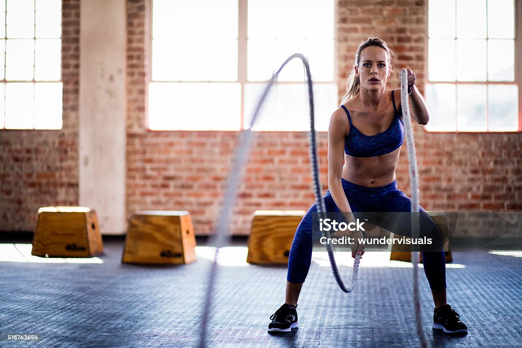 Athletic girl focused on fitness training with ropes at gym Athletic young adult girl focused on a fitness training with ropes at the gym Exercising Stock Photo