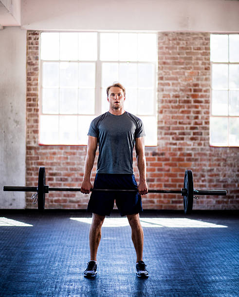 Front view of a young adult caucasian man lifting weights during a fitness training at gym