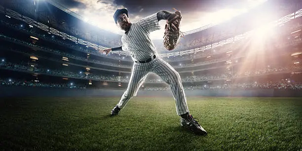 Outfielder baseball player about to throw a ball during baseball game on outdoor baseball stadium under dramatic stormy skies.