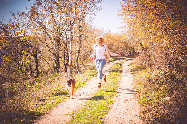 Pet owner woman is walking with her domestic dog on meadow at sunset.Sölden - Germany.