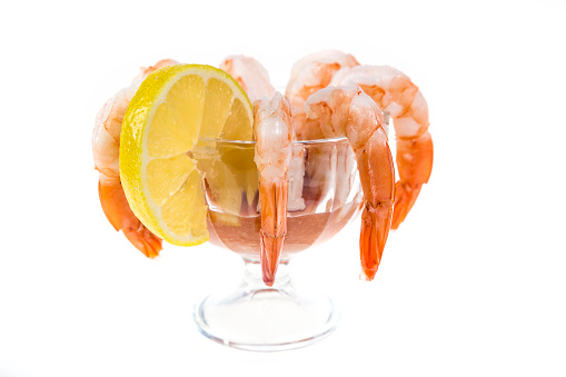 Popular appetizer shrimp cocktail in a glass serving bowl isolated on white.