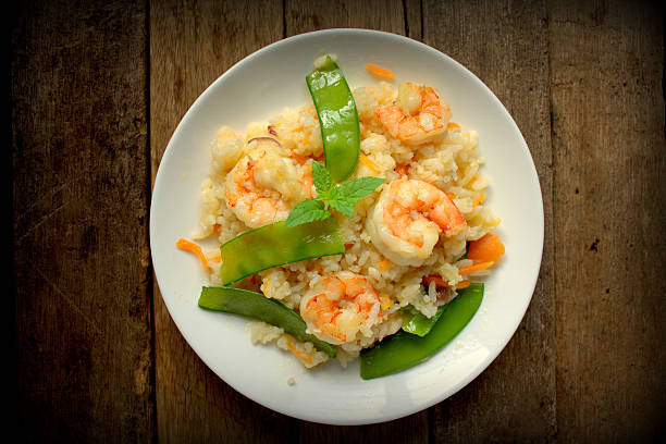 Fried rice with prawn and sweet peas, mint leave on top and classic wooden background