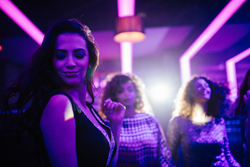 Young woman enjoying dancing with friends on the dance floor of a night club