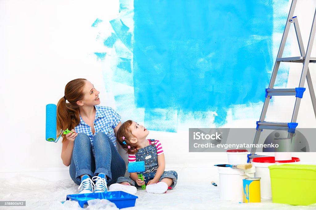 happy family mother and child daughter making repairs, paint wal happy family mother and child daughter making repairs, paint the wall at home Adult Stock Photo
