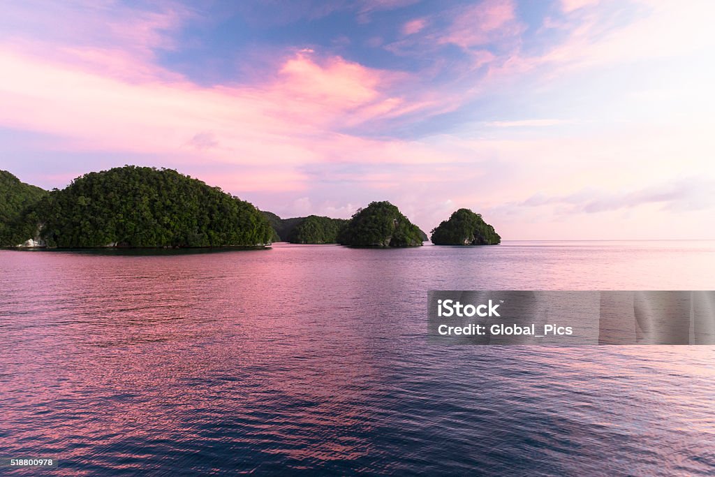 Rock Islands - Palau, Micronesia Stunning sunset at the Rock Islands of Palau, also called Chelbacheb, are a small collection of limestone or coral uprises, ancient relics of coral reefs that violently surfaced to form Islands in Palau's Southern Lagoon, between Koror and Peleliu, and are now an incorporated part of Koror State. There are between 250 to 300 islands in the group according to different sources, with an aggregate area of 47 square kilometers (18 sq mi) and a height up to 207 metres (679 ft). They are a World Heritage Site since 2012. Palau Stock Photo