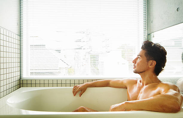 musculaire homme regardant pensivement de la fenêtre, tandis que la salle de bain - mature adult home interior chair contemporary photos et images de collection