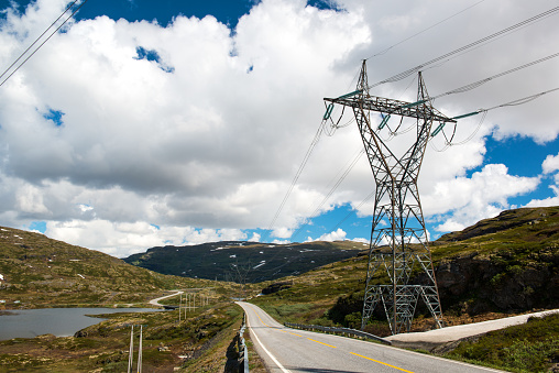 Landscape with mountain road and high voltage reliance line, blue sky with few clouds, Norway