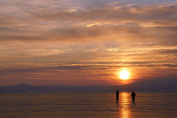 Two men are walking along the sunny path at sunset. Baikal lake, Siberia
