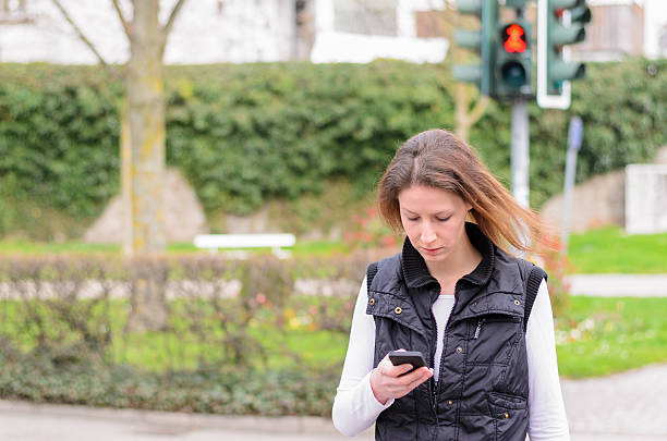 Single woman walking and looking down at phone