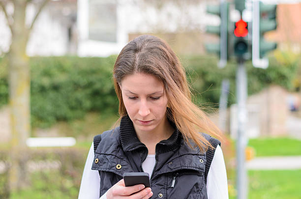 istock Single woman walking and looking down at phone 518814440