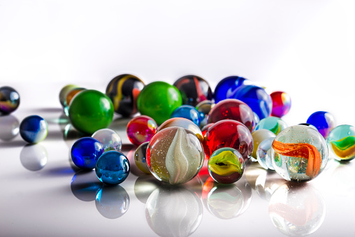 Group of mixed marbles on a reflective white surface