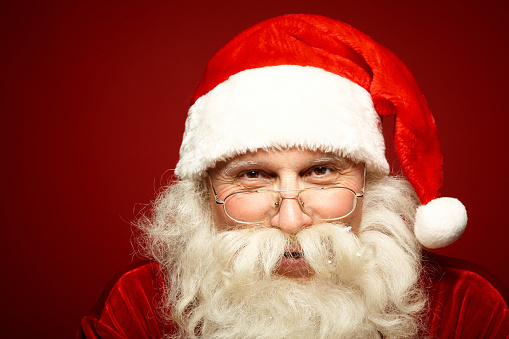 Head of positive Santa Claus in eyeglasses looking at camera