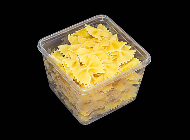 istock Uncooked farfalle pasta in plastic tray on a dark background 518827124