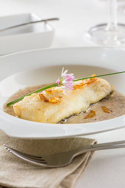 Hake fillet with garlic A fried hake fillet served a garlic sauce and garnished with fried garlic slices. hake stock pictures, royalty-free photos & images