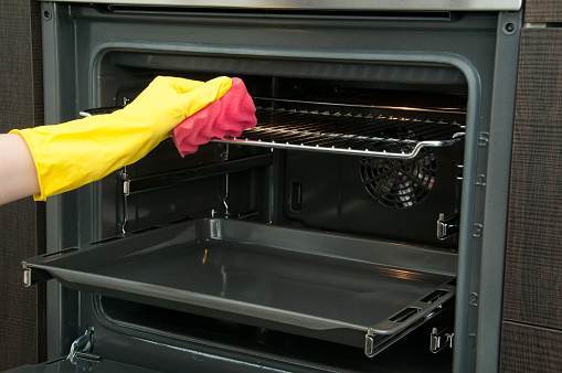 Close up of woman cleaning oven at home kitchen