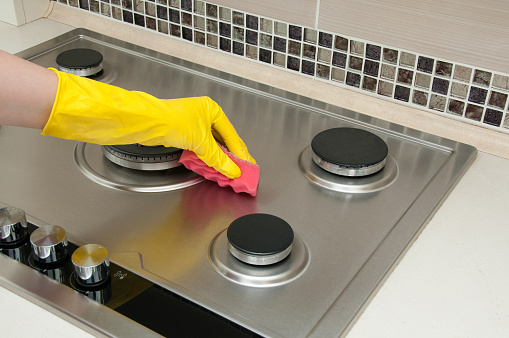 Close up of woman cleaning cooker at home kitchen
