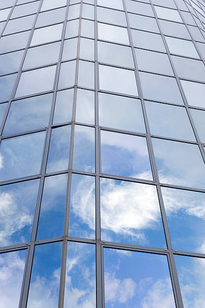 istock modern glass building with reflections of blue sky and clouds 518833218